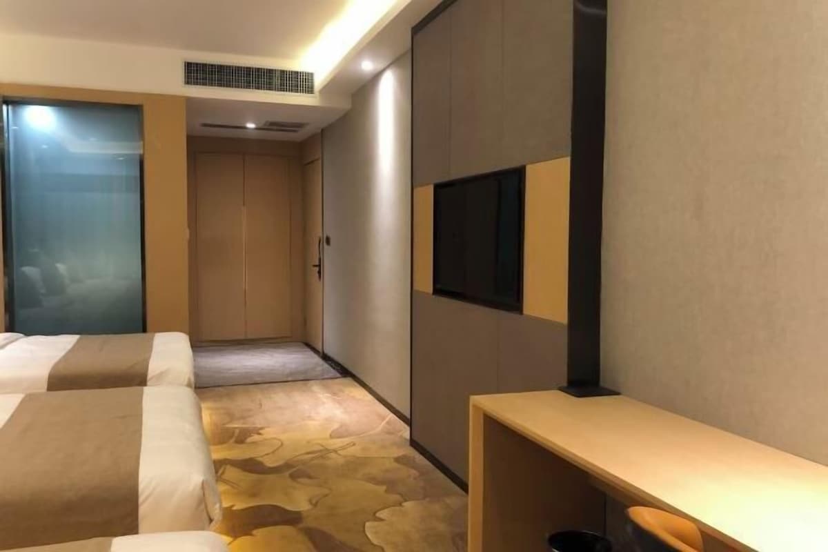 Una habitación de hotel con cama, escritorio, televisión y armario.