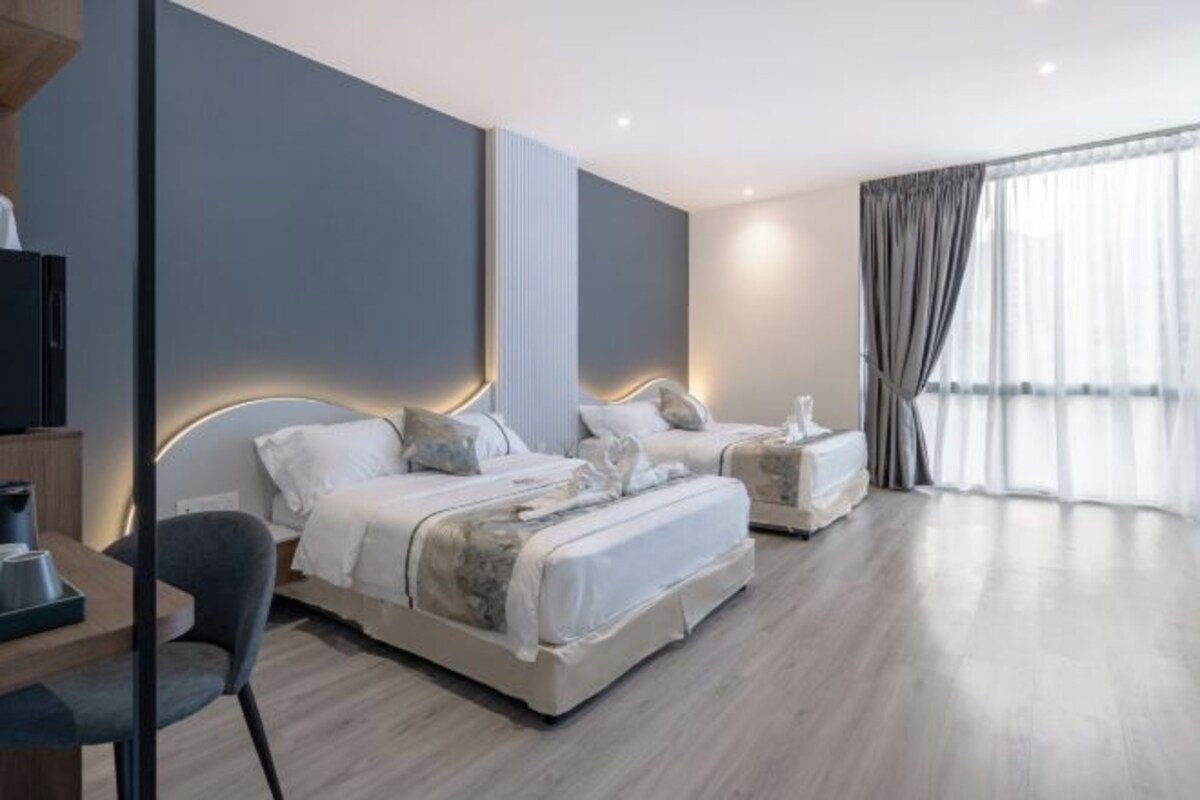 Ein modernes Hotelzimmer mit zwei Betten, einem Schreibtisch und einem Sessel.