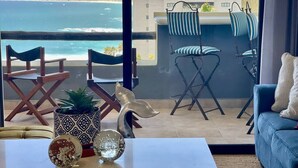 A balcony with a view of the ocean, a sofa, chairs, and decorative items. - Spectacular Ocean-View  Pet friendly Condo. Walk to Beach, Bars & Dining (Cabo Bello)