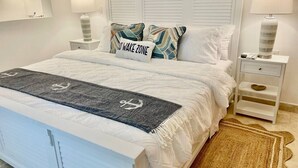 A neatly arranged bedroom with a bed, pillows, a bedside table, and a nightstand. - Spectacular Ocean-View  Pet friendly Condo. Walk to Beach, Bars & Dining (Cabo Bello)