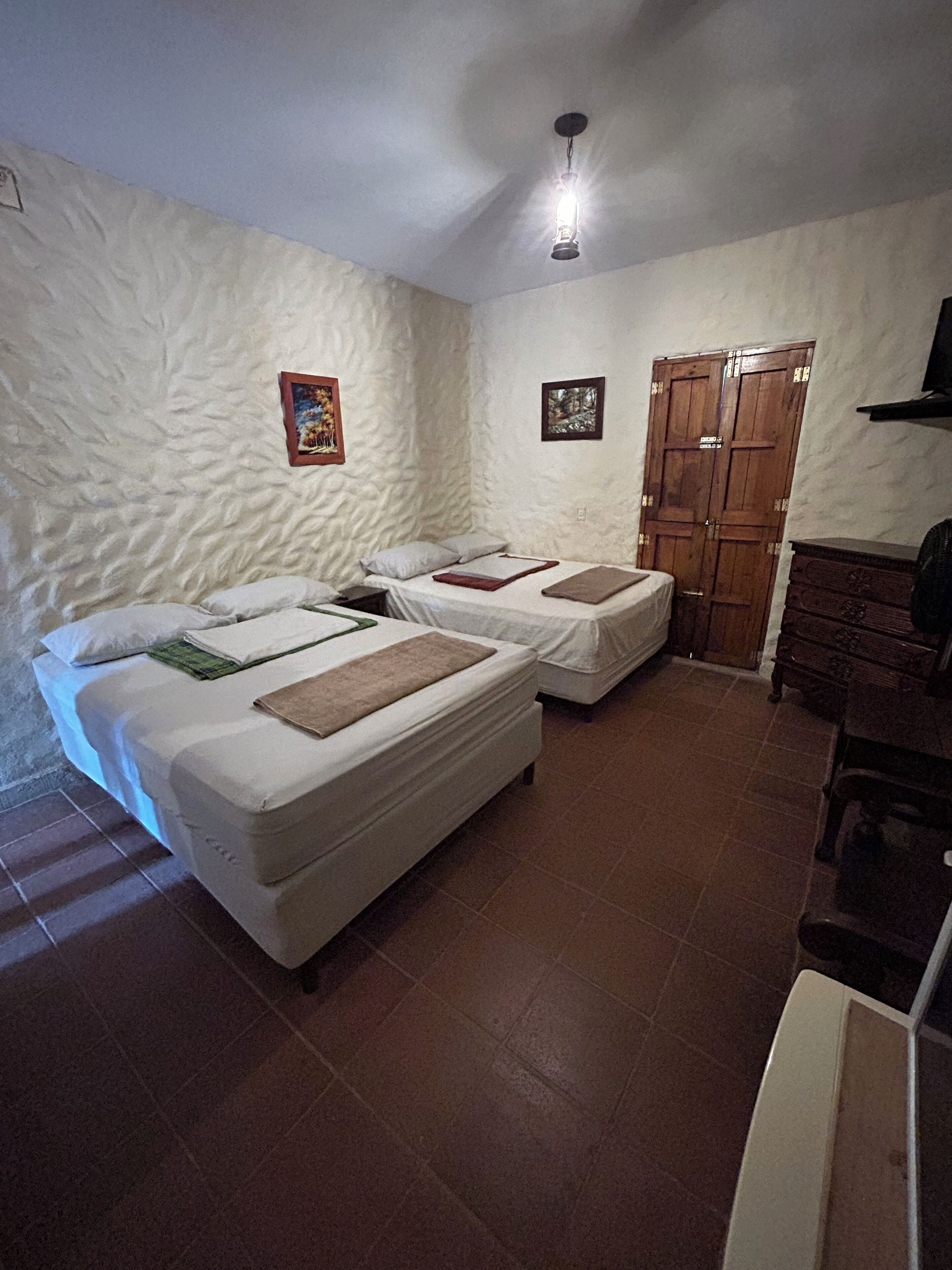 Una habitación con dos camas, un armario de madera y un pequeño escritorio.