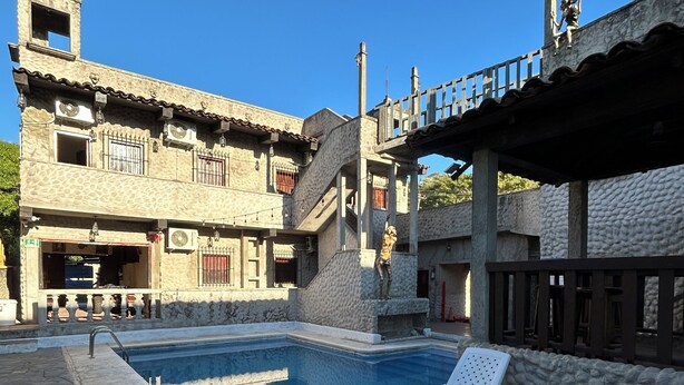 Un espace piscine avec des chaises longues et un bâtiment doté de nombreux balcons.