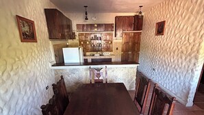 Un coin repas avec une table et des chaises en bois, une cuisine à l’arrière-plan et des murs à texture.