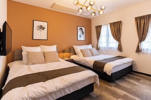 A hotel room with two beds, a chandelier, artwork on the walls, and curtains on the windows.