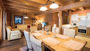 Een gezellig houten blokhutinterieur met een eethoek, bank en keuken.