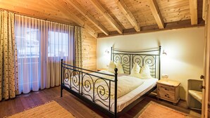 Een slaapkamer in een houten hutje, met een metalen bed, nachtkastje en klein nachttafeltje.