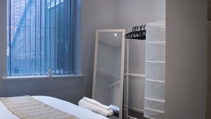 A bedroom with a large bed, a window with blinds, a wardrobe, and a radiator. - Spacious Apartment In City Centre - Free Parking (Nottingham)
