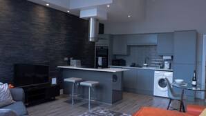 A modern kitchen with grey cabinets, a central island, and a built-in oven. - Spacious Apartment In City Centre - Free Parking (Nottingham)