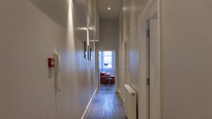 A hallway with a fire alarm, a radiator, and a door leading to a room with a window. - Spacious Apartment In City Centre - Free Parking (Nottingham)