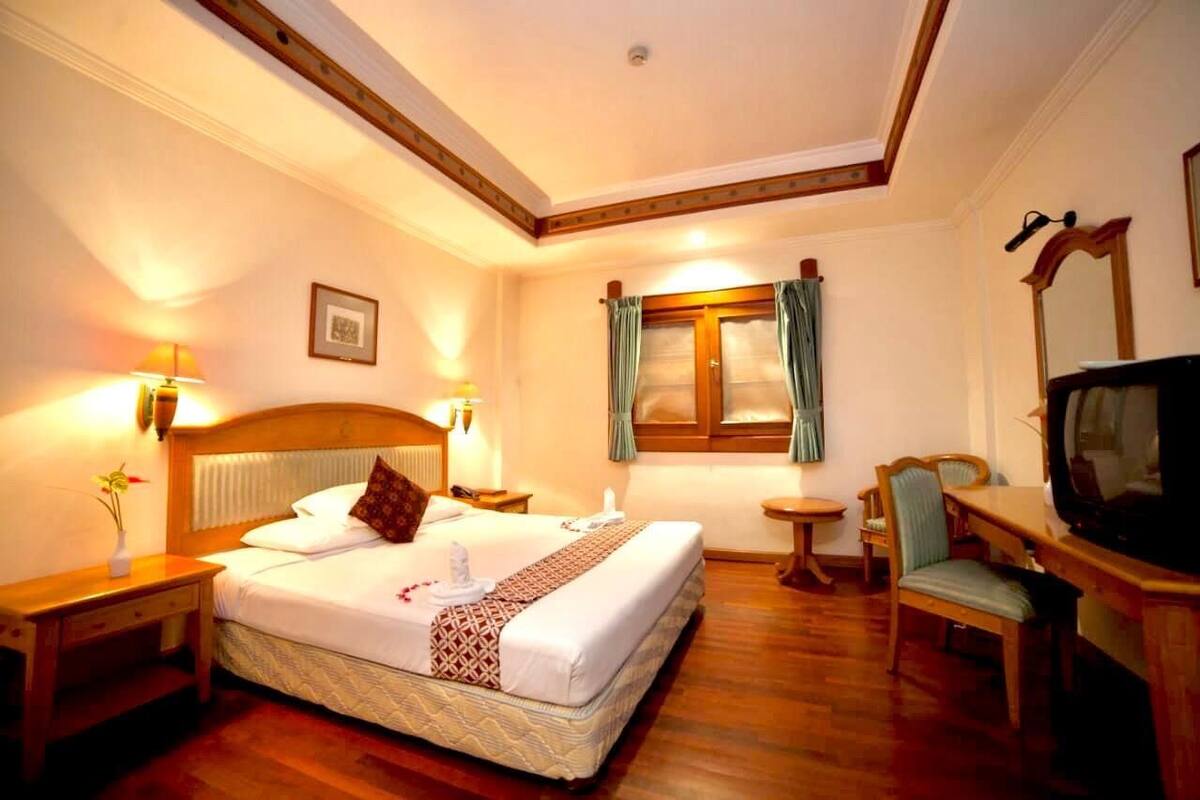 Une chambre d’hôtel avec un grand lit, des lampes de chevet, une télévision, une petite table et une chaise.