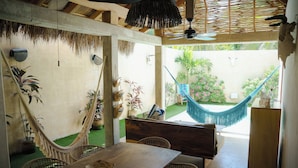 A dining area with a wooden table and chairs, a hammock, and potted plants. - Villa Noyollo Punta Pérula, Jalisco (Pérula)