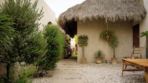 A pathway leading to a thatched-roof structure with potted plants and a wooden bench. - Villa Noyollo Punta Pérula, Jalisco (Pérula)