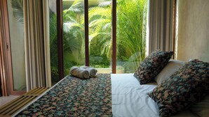 A hotel room with a bed, a window with curtains, and a view of palm trees. - Villa Noyollo Punta Pérula, Jalisco (Pérula)