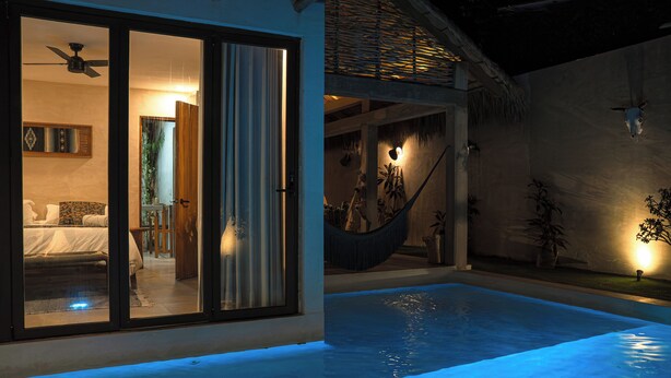 A modern pool area with a glass-enclosed room, a hammock, and a thatched roof structure. - Villa Noyollo Punta Pérula, Jalisco (Pérula)