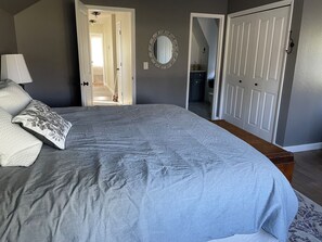 A bedroom with a large bed, a dresser, a mirror, and a door leading to another room. - Spacious 4-bedroom house in lovely Walla Walla with pool and fitness room (Walla Walla)