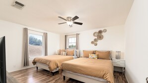 A bedroom with two beds, a ceiling fan, a TV, and a window with curtains. - Spacious 4BR w Game Room - 15 min to Seaworld (San Antonio)