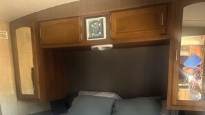 Quarto com cama, um armário de madeira e um espelho.