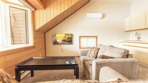 Ein gemütliches Wohnzimmer mit einer Couch, einem kleinen Tisch und einem Bild an der Wand.