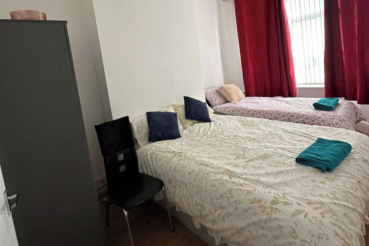 A room with two beds, a chair, and a desk.