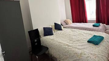 A room with two beds, a chair, and a desk.
