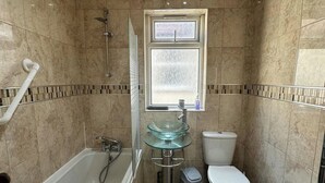 A bathroom with a bathtub, glass sink, toilet, and a window. - 4 Bed House - Sleeps 10 - Garden - Parking - Wifi (Doncaster)
