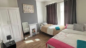 A bedroom with two beds, a mirror, a dresser, and a fireplace. - 4 Bed House - Sleeps 10 - Garden - Parking - Wifi (Doncaster)