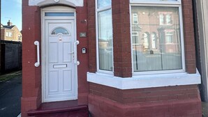 A red brick house with a white front door and a large window. - 4 Bed House - Sleeps 10 - Garden - Parking - Wifi (Doncaster)