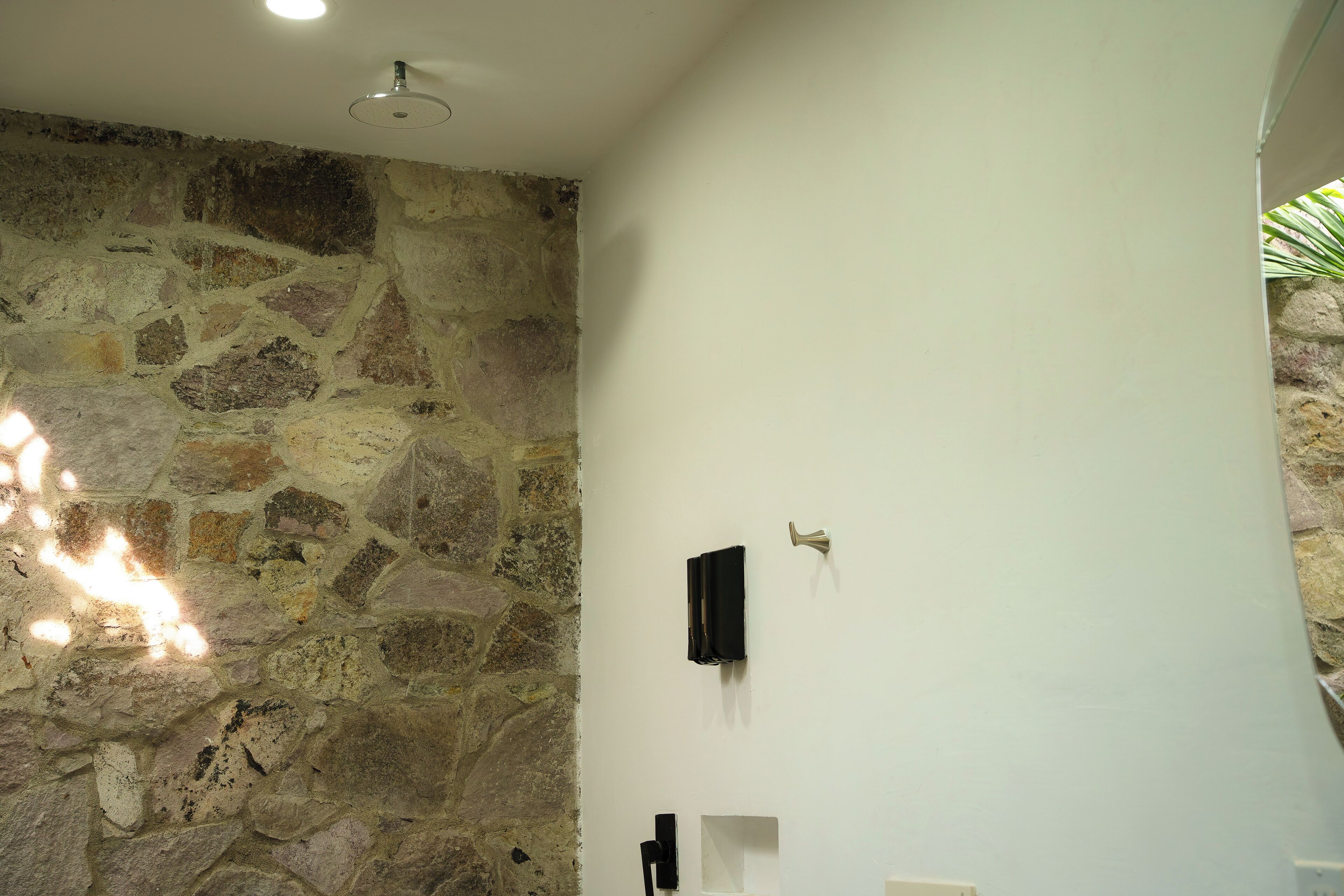 Une salle de bain avec un mur en pierre, un plafond blanc et un luminaire.