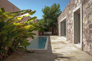 A swimming pool with stone walls and a pathway leading to a door.