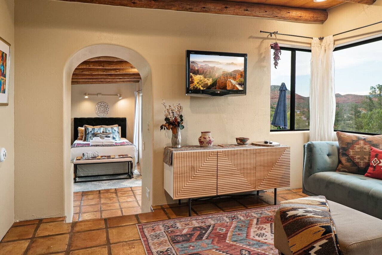 Une chambre à coucher avec un lit, une télévision, une commode et une vue sur l’extérieur.