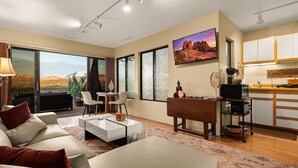 Una sala de estar moderna con un sofá, una mesa de centro y un comedor con una mesa y sillas. Hay una cocina con armarios y una encimera.
