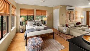 Un dormitorio con una cama, mesitas de noche, un sofá y una mesa de comedor.