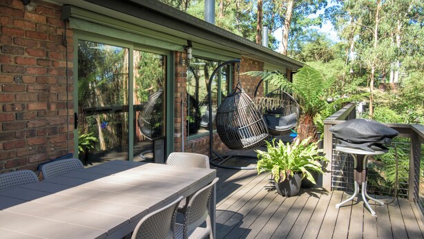 A wooden deck with a table and chairs, a hanging chair, and a grill. - Elliott Lodge - family & pet friendly (Upwey)