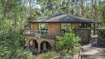 A rustic lodge with a brick exterior, a covered patio, and a stone bridge leading to the entrance.