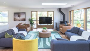 A modern living room with a large flat-screen TV, multiple sofas, and a wooden floor. - Elliott Lodge - family & pet friendly (Upwey)