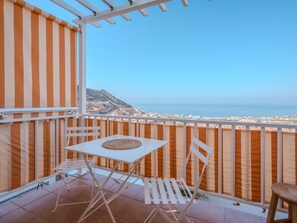 A balcony with a white table and chairs, a view of the sea, and a striped awning. - Vistalmar, Duplex in Costa Adeje (Costa Adeje)