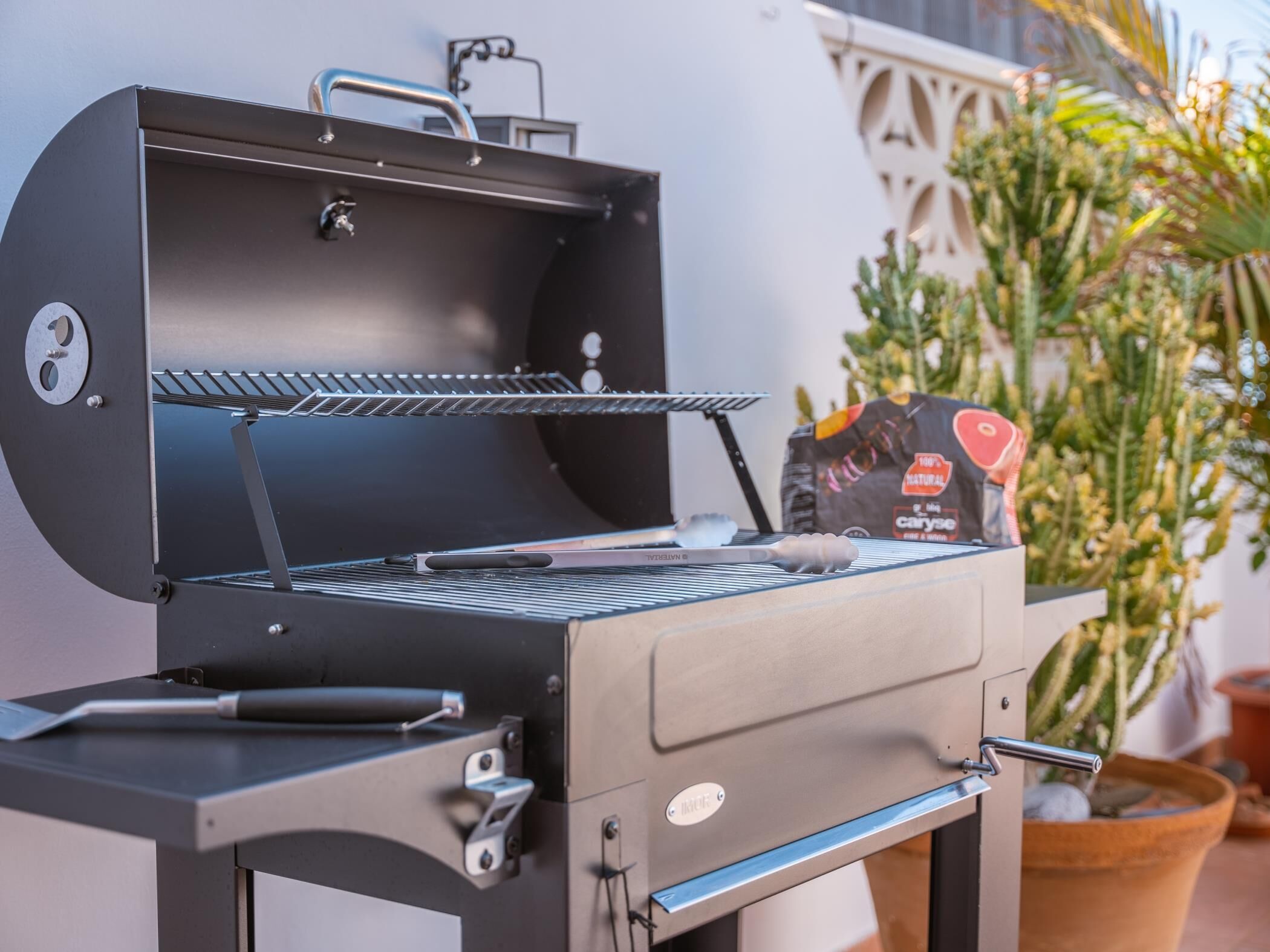 A modern outdoor grill with a control panel, a built-in thermometer, and a side drawer.