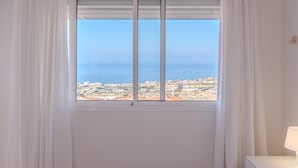 A room with a large window overlooking a coastal cityscape.
