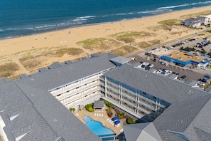 Vista aérea de un hotel con piscina, acceso a la playa y estacionamiento.