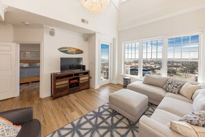 Ein geräumiges Wohnzimmer mit großem Fenster, Fernseher und einer Couch.