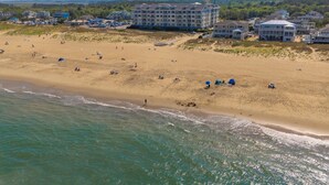 Vista aérea de una playa con un complejo hotelero al fondo.