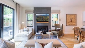 A modern living room with a fireplace, comfortable seating, and a large TV screen. - Alpine House in Ketchum with Casita + Hot Tub (Ketchum)