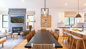 A modern kitchen with white cabinets, a large island, and a hanging light fixture. - Alpine House in Ketchum with Casita + Hot Tub (Ketchum)
