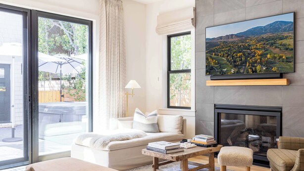 A modern living room with a sofa, coffee table, and armchairs, a fireplace, and a large TV mounted on the wall. - Alpine House in Ketchum with Casita + Hot Tub (Ketchum)
