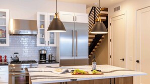 A modern kitchen with stainless steel appliances, a marble island, and pendant lighting. - Alpine House in Ketchum with Casita + Hot Tub (Ketchum)