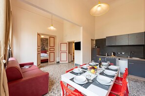 A modern kitchen with dark cabinets, a dining table set with plates, glasses, and a fruit bowl.