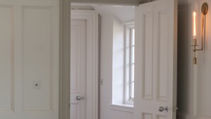 Une pièce avec une table à plateau en verre, un fauteuil blanc moelleux et des portes blanches.