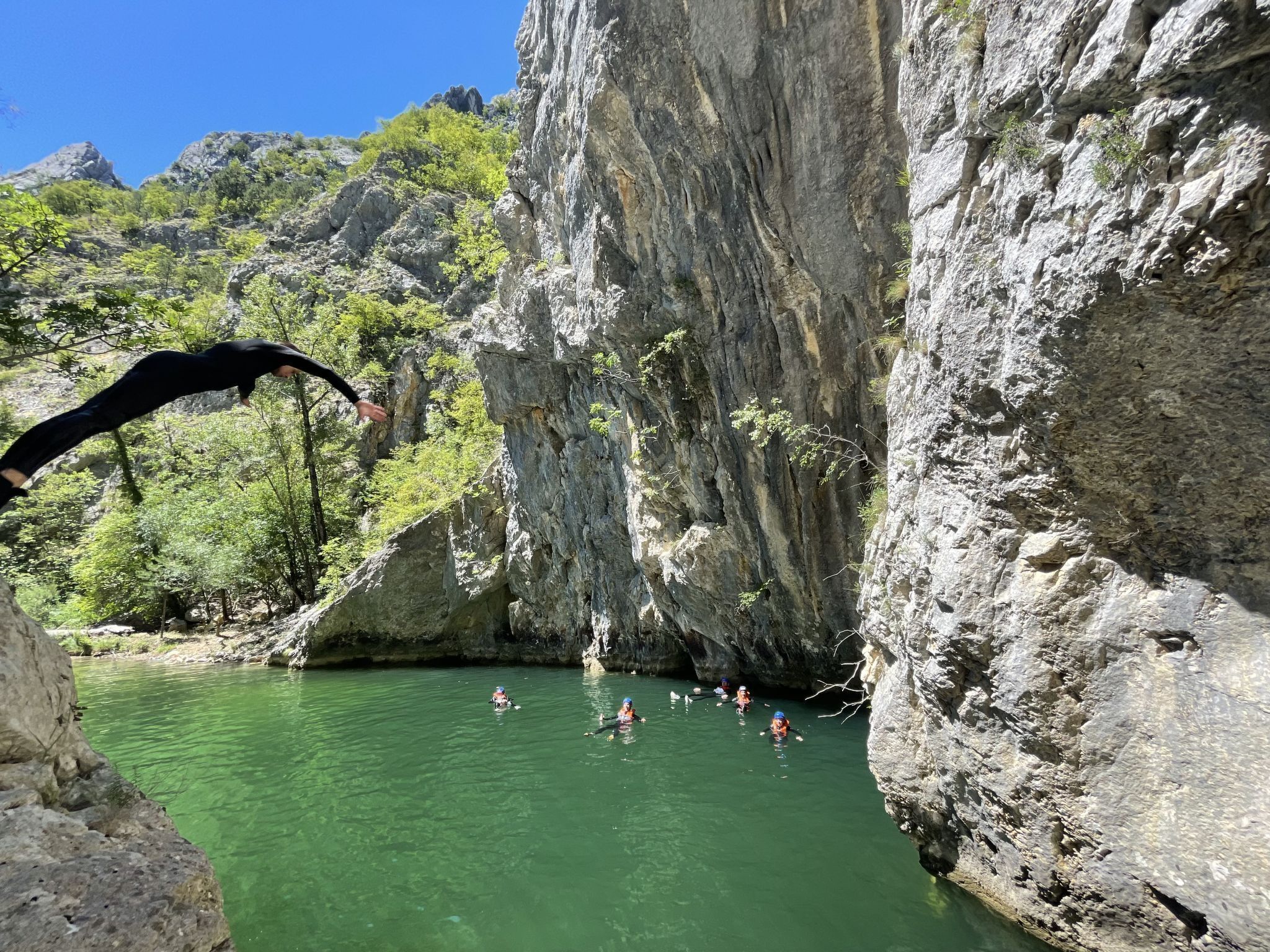 A natural swimming area surrounded by rocky cliffs and greenery.