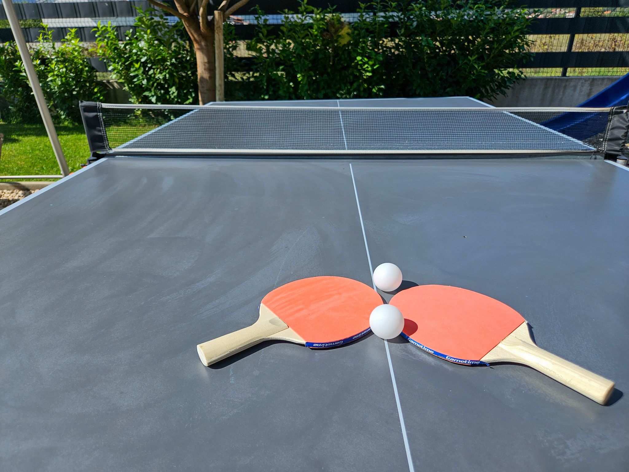A ping pong table with two paddles and two balls.
