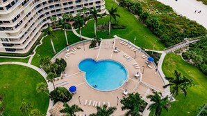 A hotel with a circular pool, palm trees, and a multi-story building. - Modern 2BR Condo l Gorgeous Oceanview (Marco Island)